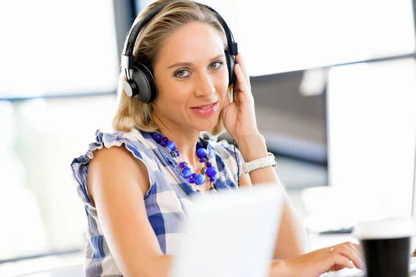 Mujer joven en la oficina con auriculares —  Fotos de Stock