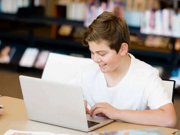 Teenage boy with tablet in library — Stock Photo, Image