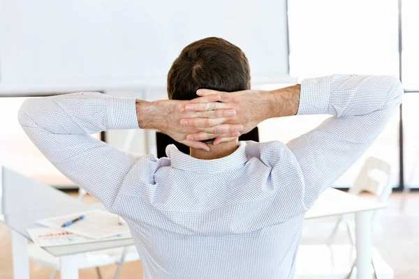 Rear view of sitting businessman with crossed hands on the head — Stock Photo, Image