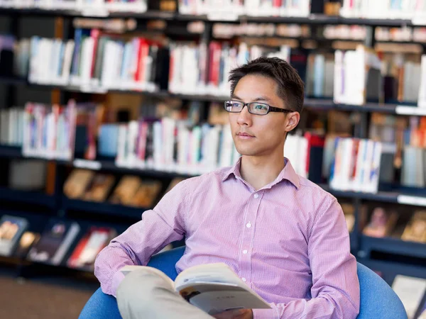 Glücklicher männlicher Student mit Büchern in der Bibliothek — Stockfoto