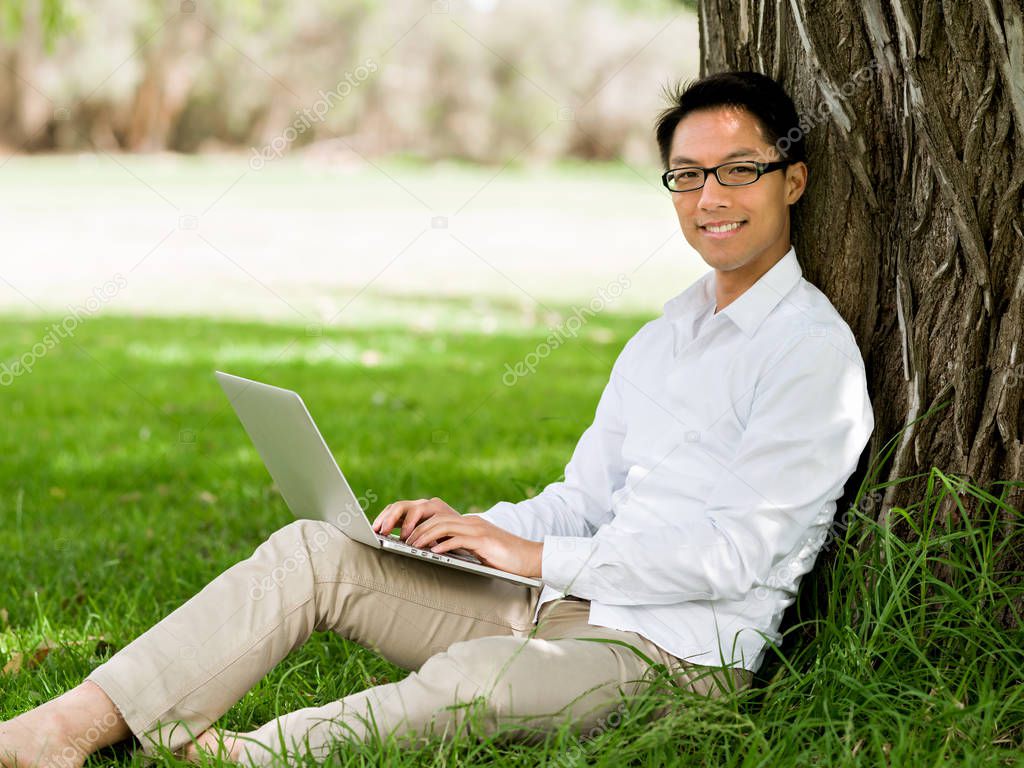 Young businessman using laptop while sitting outdoors