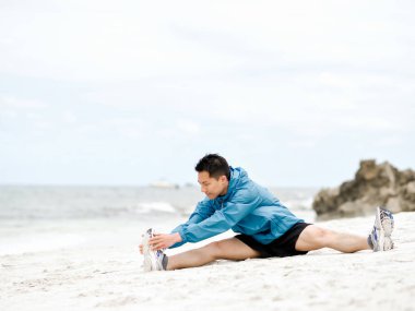 Genç adam sahilde egzersiz yaparak