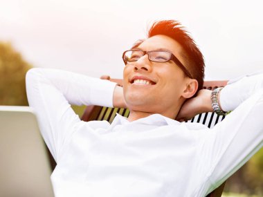 Genç işadamı açık havada otururken dizüstü bilgisayar kullanarak