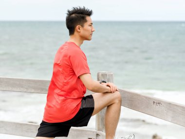 Genç adam sahilde egzersiz yaparak