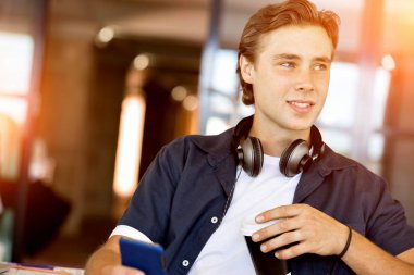 Kendine güvenen genç adam akıllı rahat kıyafet telefon tutarak