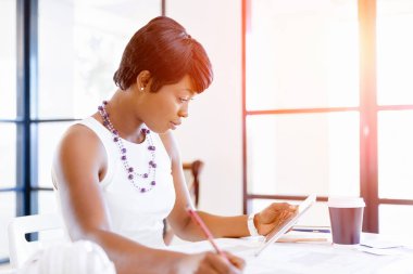 Bir ofiste bir masada oturan ve plan üzerinde çalışan genç kadın