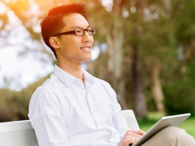 Genç işadamı açık havada otururken dizüstü bilgisayar kullanarak