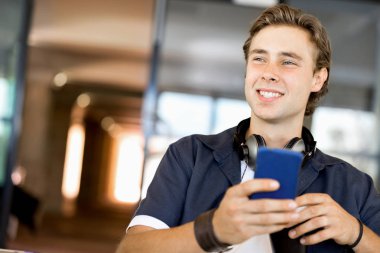 Kendine güvenen genç adam akıllı rahat kıyafet telefon tutarak