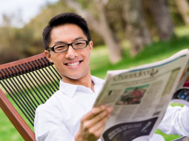 İş adamı parkta bir gazete okuyor