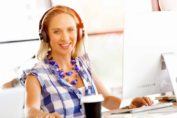 Young woman in the office with headphones — Stock Photo, Image