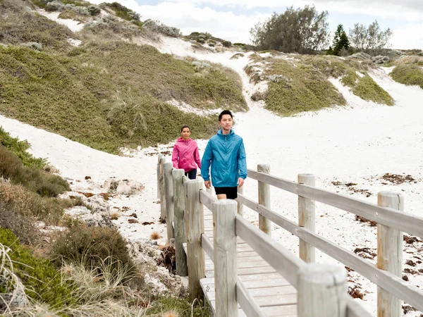 Молодая пара бежит вдоль берега моря — стоковое фото