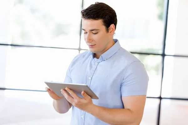 Jeune homme d'affaires beau utilisant son pavé tactile debout dans le bureau — Photo