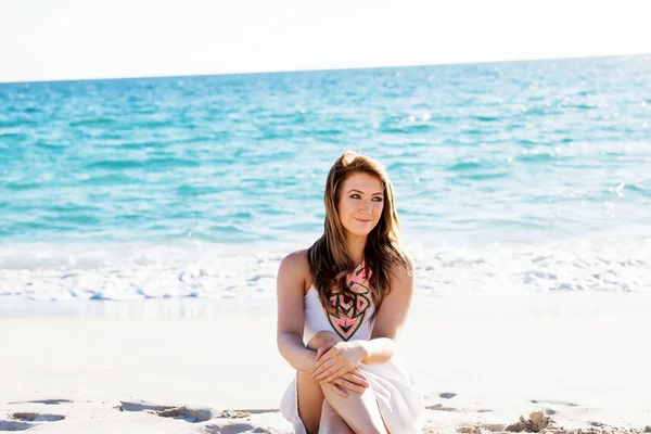 Jonge vrouw zittend op het strand — Stockfoto