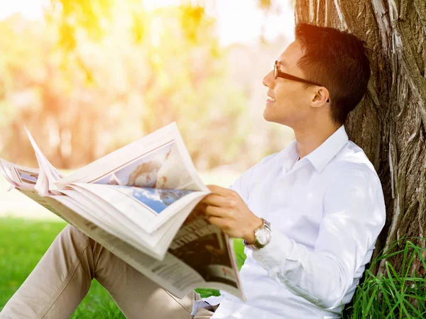 İş adamı parkta bir gazete okuyor