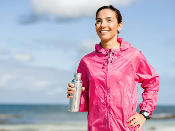 Bella ragazza in vestiti sportivi acqua potabile dopo l'allenamento sulla spiaggia — Foto Stock