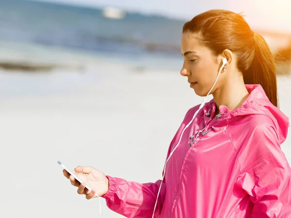 Sportovní žena s sluchátka na pobřeží moře — Stock fotografie