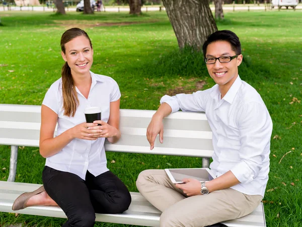 Ritratto di coppia sorridente seduta nel parco a parlare — Foto Stock
