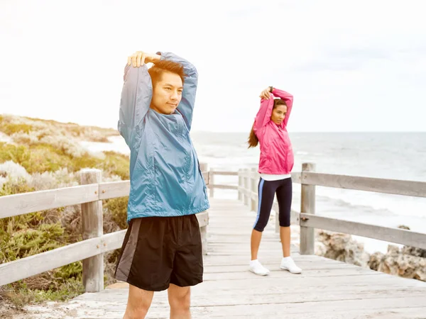 Jeune couple au bord de la mer faisant des exercices — Photo