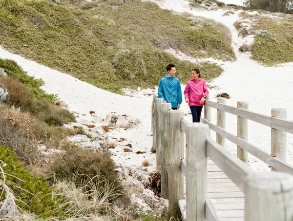 Jonge man en vrouw in sportkleding wandelen op het strand — Stockfoto