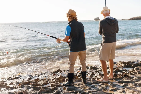 Uomo anziano pesca con suo nipote — Foto Stock