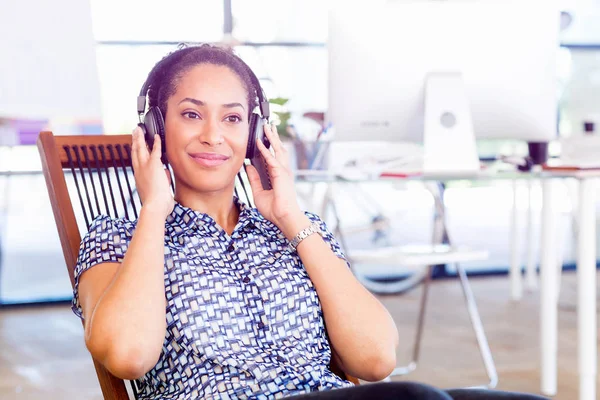 Portrait of smiling afro-american office worker sitting in offfice with headphones — Stock Photo, Image