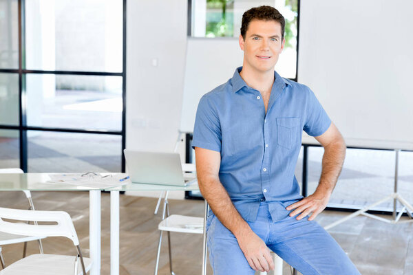 Young business man sitting on a stool in office