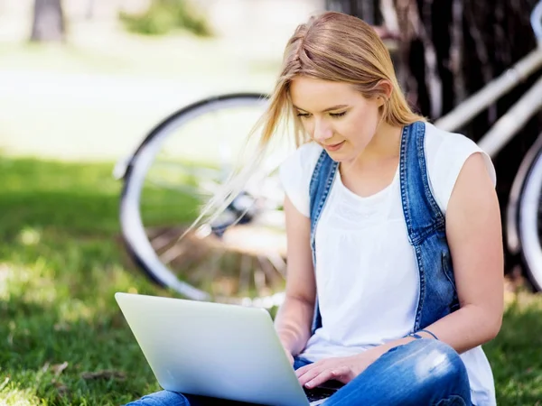 Mujer trabajando al aire libre en un prado con portátil —  Fotos de Stock