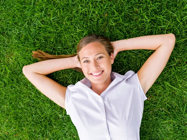 Jovem mulher bonita relaxante em uma grama — Fotografia de Stock