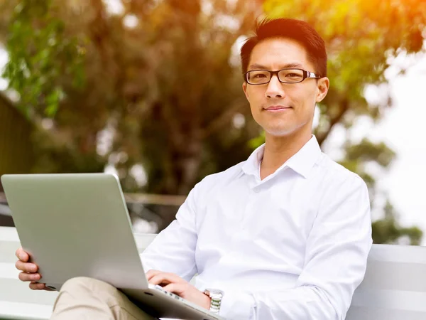 Молодой бизнесмен, сидя на улице, пользуется ноутбуком — стоковое фото