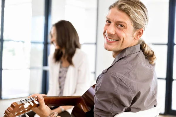 Jeune homme jouant de la guitare au bureau — Photo