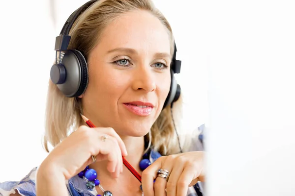 Young woman in the office with headphones Stock Picture