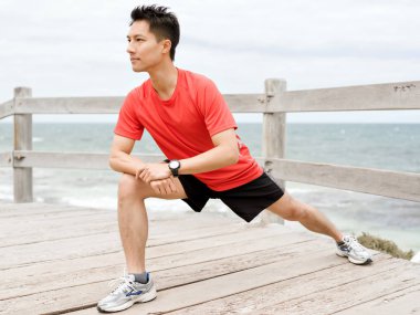 Genç adam sahilde egzersiz yaparak