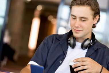 Kendine güvenen genç adam akıllı rahat kıyafet telefon tutarak