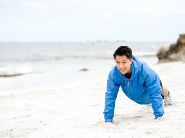 Genç adam sahilde egzersiz yaparak