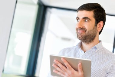 Genç yakışıklı işadamı onun touchpad ayakta kullanma office