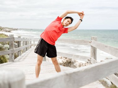 Genç adam sahilde egzersiz yaparak