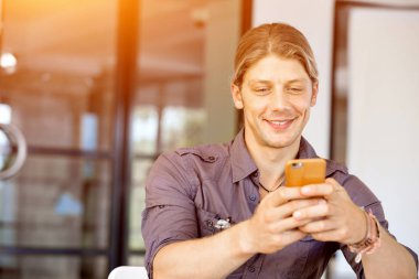 Kendine güvenen genç adam akıllı rahat kıyafet telefon tutarak