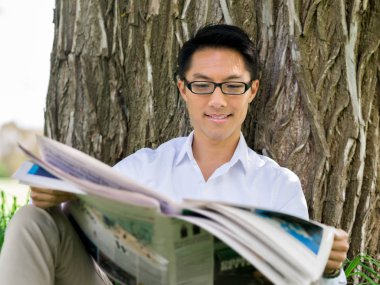 İş adamı parkta bir gazete okuyor