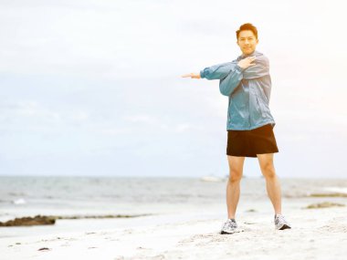 Genç adam sahilde egzersiz yaparak