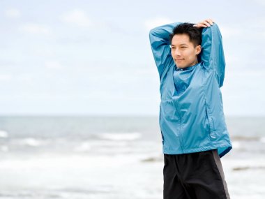 Genç adam sahilde egzersiz yaparak