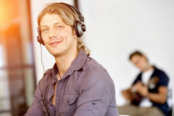 Νεαρός άνδρας στο γραφείο με τα ακουστικά — Φωτογραφία Αρχείου