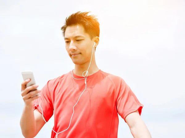 Sporty man with earphones on the sea coast — Stock Photo, Image