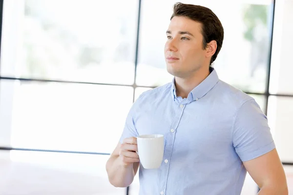 Young businessman in office with a mug — Stock Photo, Image