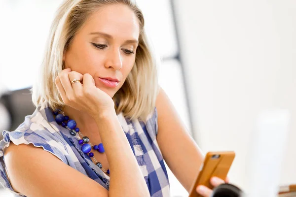 Ung kvinna i fritidskläder som håller telefonen — Stockfoto