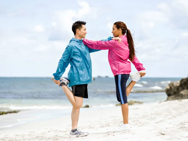 Νεαρό ζευγάρι στην παραλία κάνοντας ασκήσεις — Φωτογραφία Αρχείου
