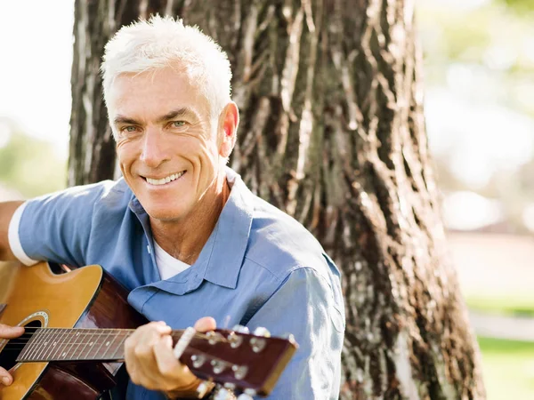Senior man varen gitaar buitenshuis — Stockfoto