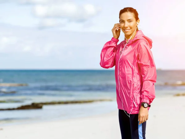 Sportieve vrouw met koptelefoon aan de kust van de zee — Stockfoto