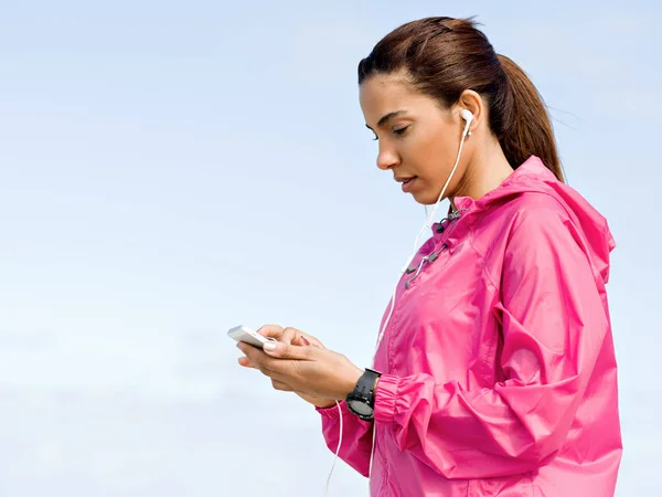 Sporty woman with earphones on the sea coast — Stock Photo, Image