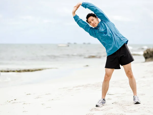 Jonge man doen oefening op het strand — Stockfoto