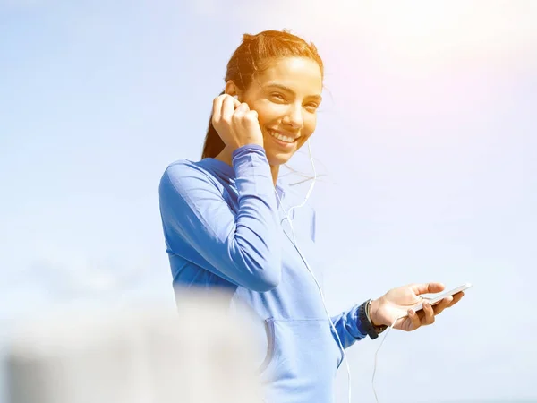 Sporty woman with earphones on the sea coast — Stock Photo, Image